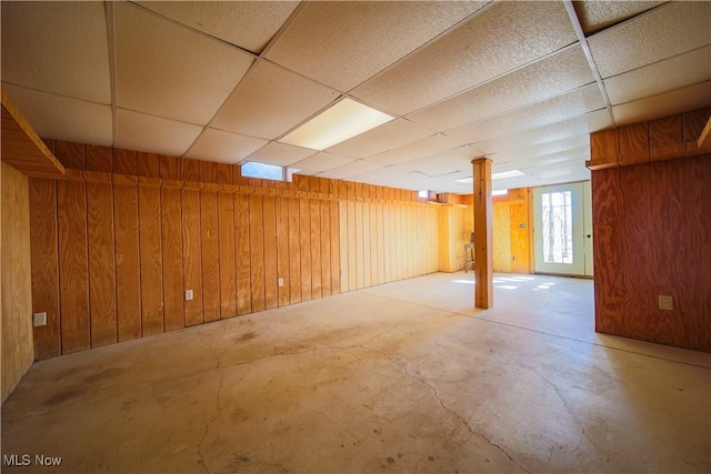 basement with a drop ceiling and wood walls