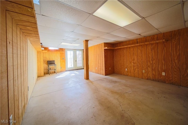 basement with wooden walls and a paneled ceiling