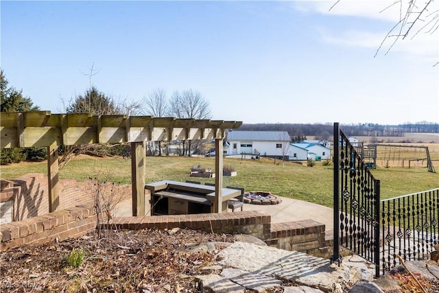 view of yard with a pergola, a fire pit, and fence