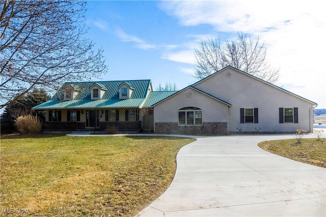 view of front of home with a porch, concrete driveway, a front yard, metal roof, and stone siding