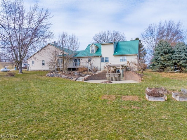 back of house featuring a lawn, a deck, a vegetable garden, metal roof, and a patio area