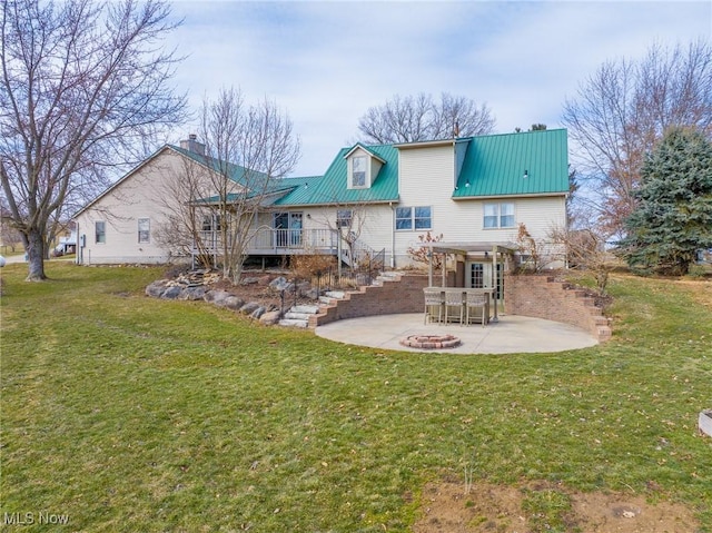 rear view of property featuring stairway, a lawn, metal roof, a deck, and a patio