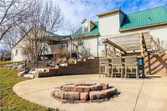 exterior space with outdoor dry bar, a fire pit, stairway, metal roof, and a patio