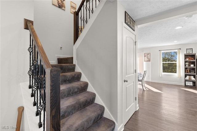 stairs with recessed lighting, wood finished floors, baseboards, and a textured ceiling