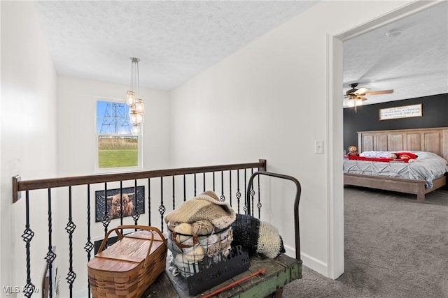 corridor with a chandelier, a textured ceiling, baseboards, and carpet floors