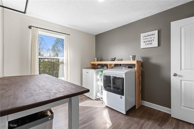 washroom featuring washer and dryer, laundry area, wood finished floors, and baseboards