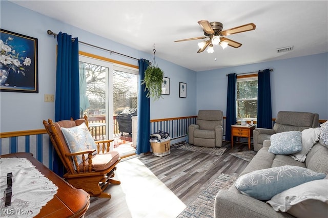 living area with ceiling fan, visible vents, and wood finished floors