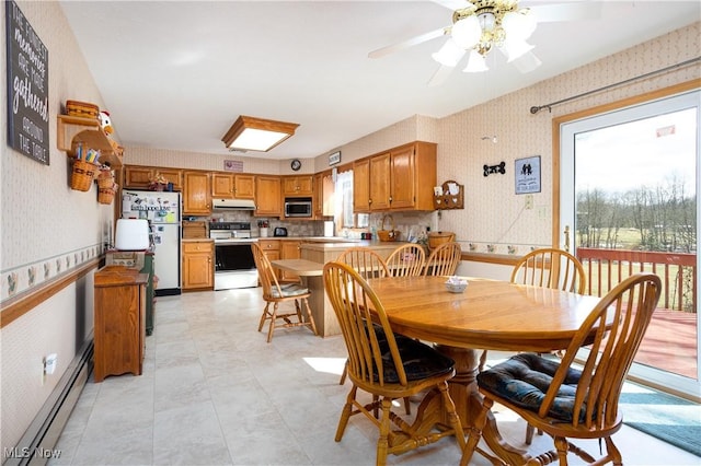 dining area featuring a baseboard radiator, a healthy amount of sunlight, wainscoting, and wallpapered walls