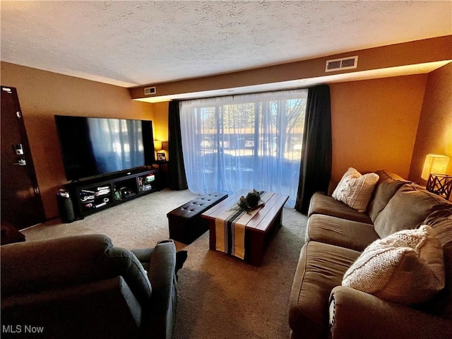 living room featuring visible vents, carpet flooring, and a textured ceiling