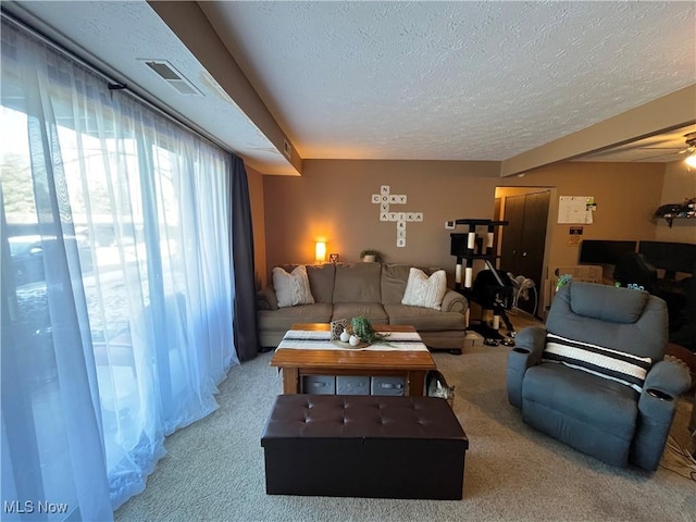 carpeted living room featuring visible vents, a textured ceiling, and ceiling fan