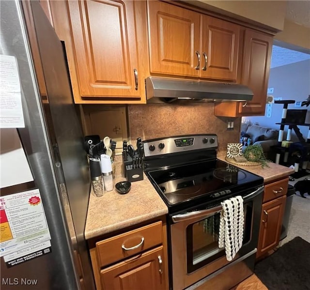 kitchen featuring tasteful backsplash, light countertops, range hood, brown cabinetry, and stainless steel appliances