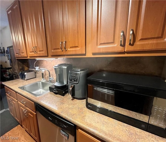 kitchen featuring stainless steel dishwasher, light countertops, black microwave, and a sink