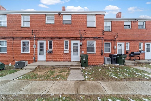 multi unit property featuring cooling unit, brick siding, and a chimney