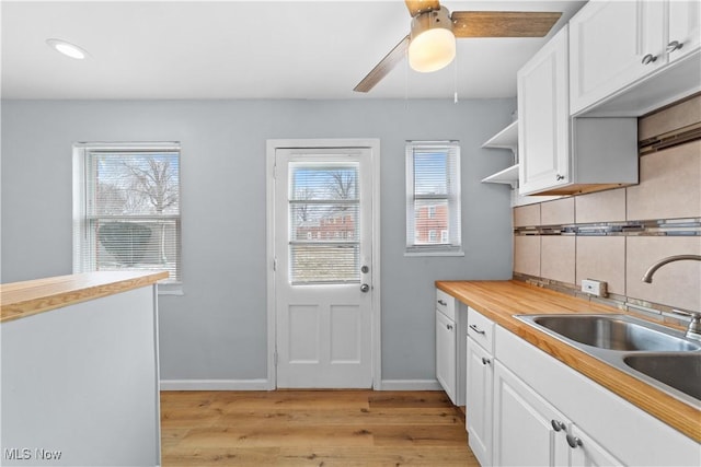 kitchen with a sink, decorative backsplash, light wood-style floors, white cabinets, and open shelves