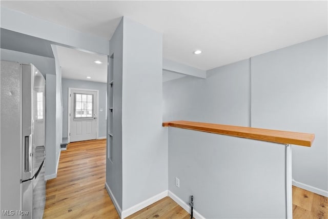 hallway with light wood-style flooring, recessed lighting, and baseboards