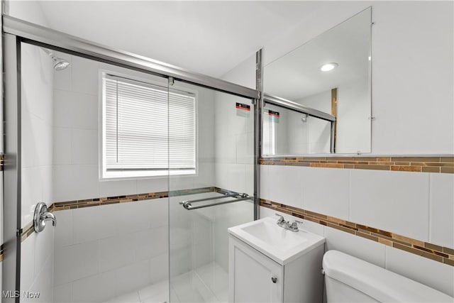 bathroom featuring toilet, a stall shower, tile walls, and vanity