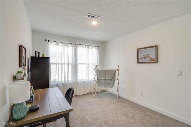 carpeted home office featuring baseboards, visible vents, and a textured ceiling