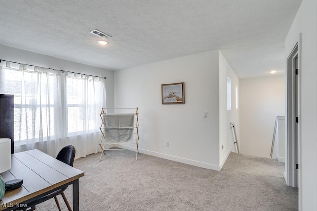 office area featuring baseboards, light colored carpet, visible vents, and a textured ceiling