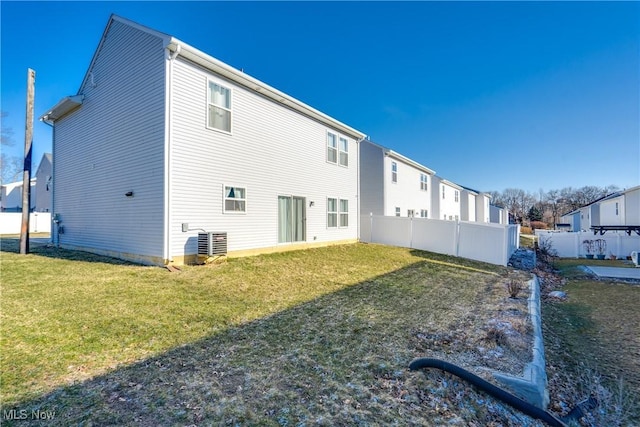 back of property with cooling unit, a yard, and fence