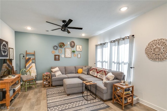 living room with a ceiling fan, baseboards, and light wood finished floors