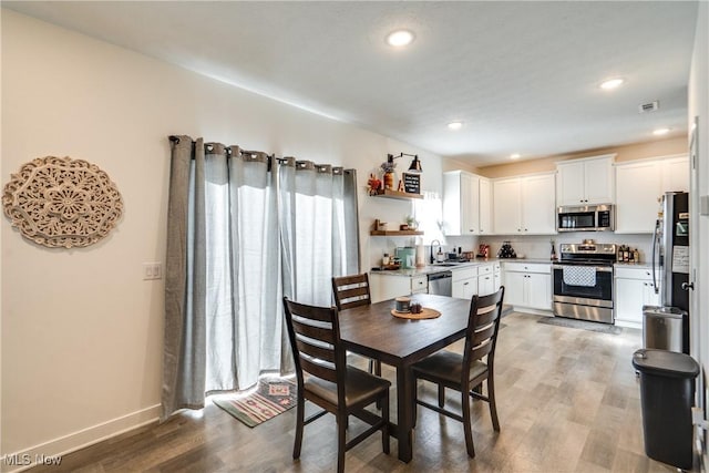 dining room featuring light wood finished floors, visible vents, recessed lighting, and baseboards