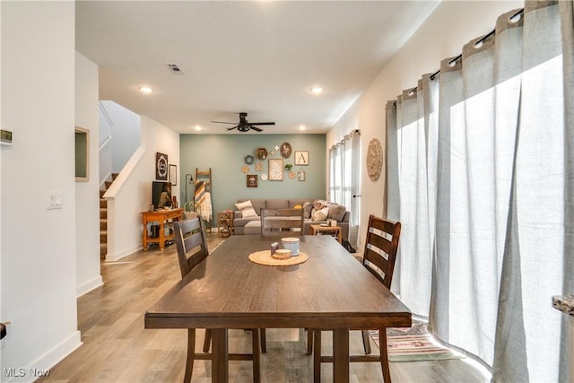 dining area featuring stairs, baseboards, visible vents, and light wood finished floors