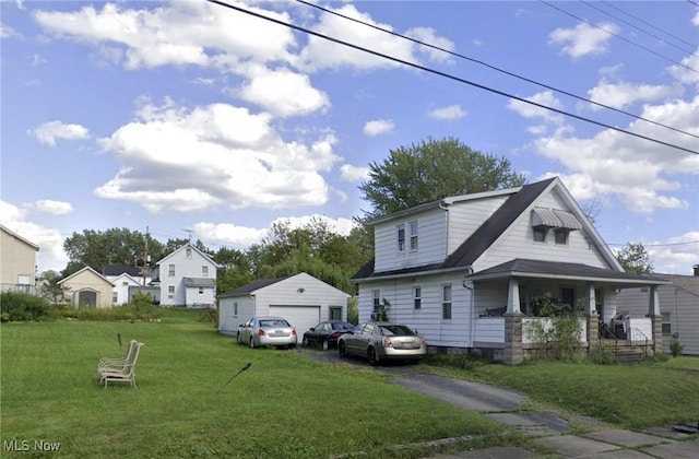 view of front of house with a garage, an outbuilding, a porch, and a front lawn