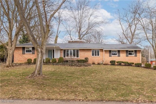 ranch-style house featuring brick siding, a chimney, and a front yard