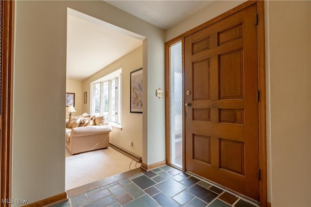 foyer entrance with stone tile floors and baseboards