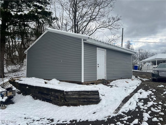 snow covered structure with an outbuilding