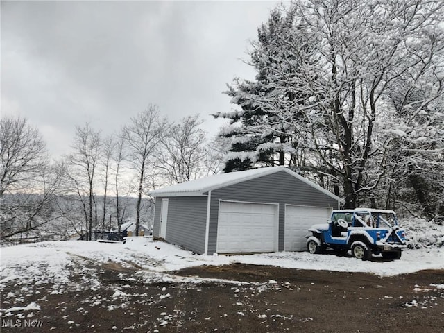 snow covered garage featuring a detached garage