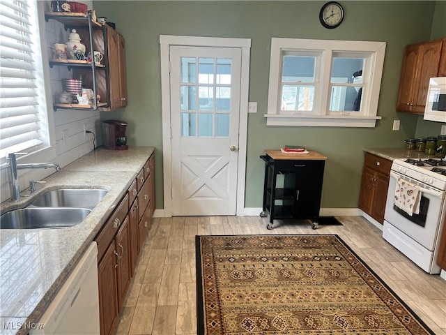 kitchen featuring a sink, white appliances, wood finish floors, and light countertops