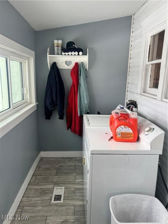 washroom with visible vents, washer and clothes dryer, laundry area, baseboards, and wood tiled floor