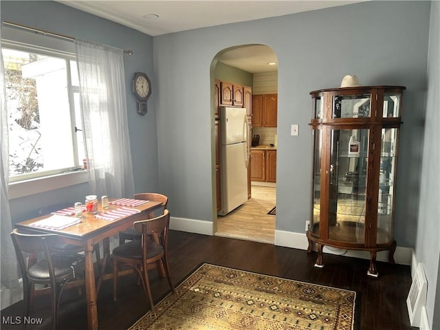 dining area featuring arched walkways, visible vents, baseboards, and light wood-style floors