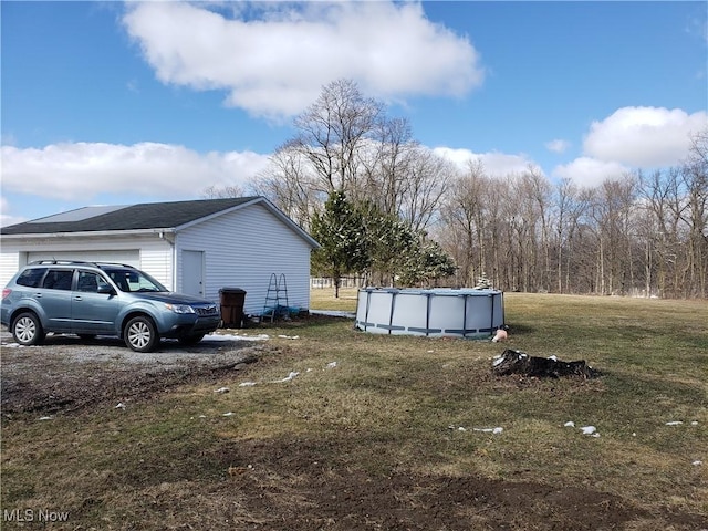 view of home's exterior with an outdoor pool, a yard, and a garage