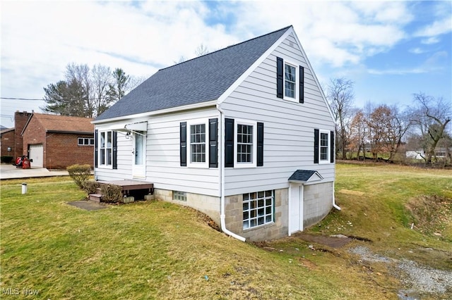 view of side of home with a yard and roof with shingles