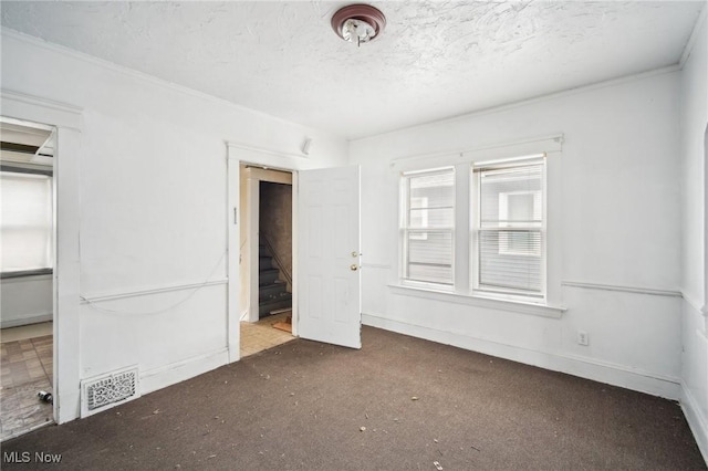 unfurnished room with stairway, baseboards, visible vents, a textured ceiling, and carpet flooring