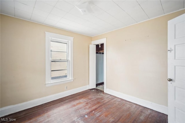 spare room with baseboards and wood finished floors