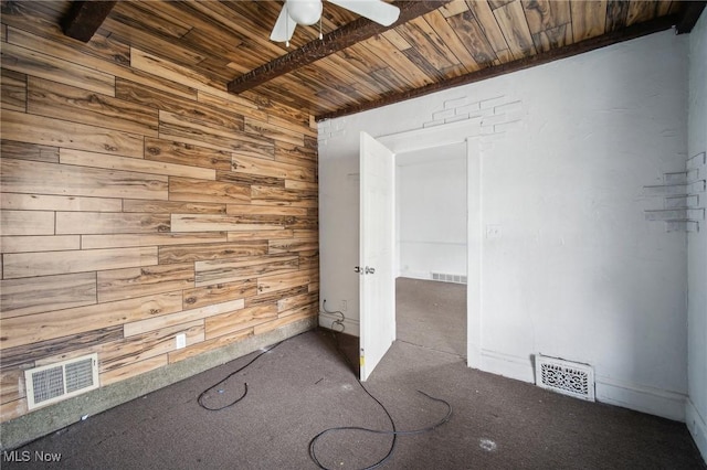 unfurnished room with visible vents, wood walls, wooden ceiling, and ceiling fan