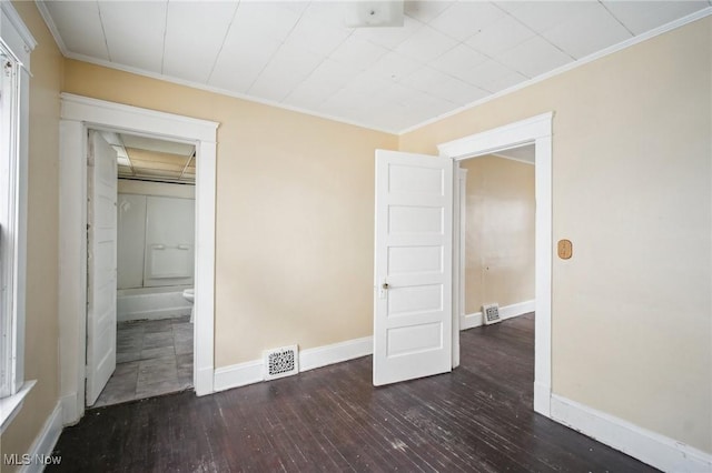 unfurnished bedroom featuring visible vents, baseboards, wood-type flooring, and ornamental molding