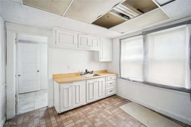 kitchen with a paneled ceiling and white cabinets