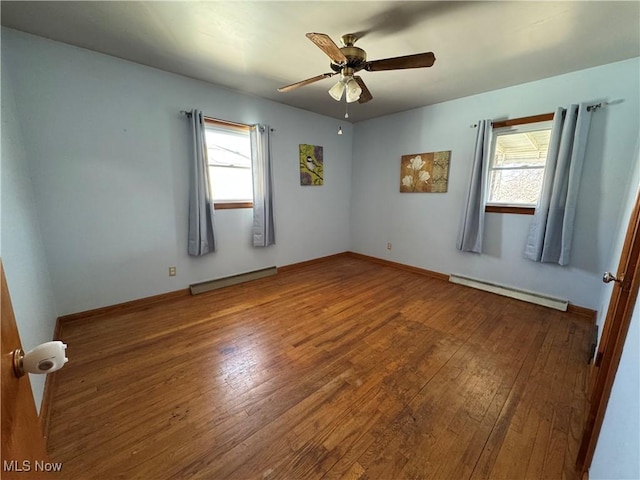 empty room featuring a baseboard heating unit, ceiling fan, and hardwood / wood-style flooring