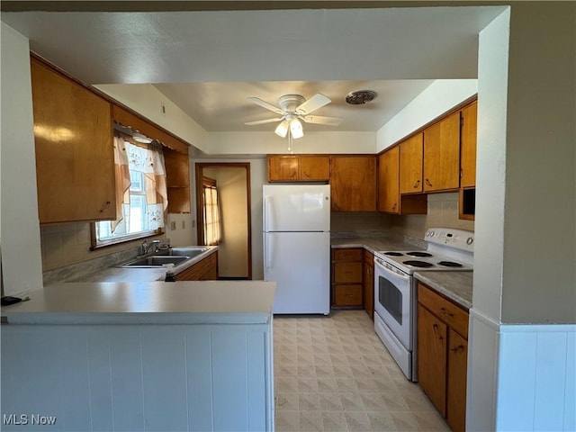 kitchen featuring a peninsula, brown cabinetry, white appliances, a ceiling fan, and a sink