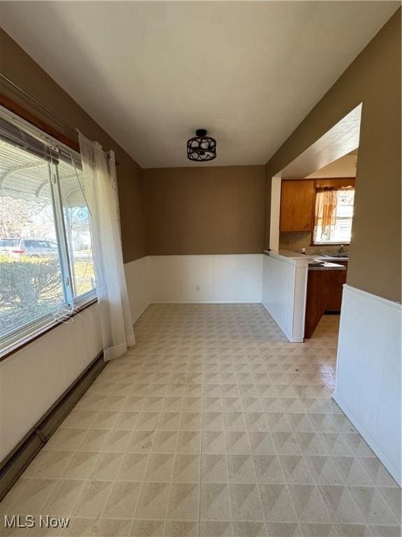 unfurnished room featuring light floors and a wainscoted wall