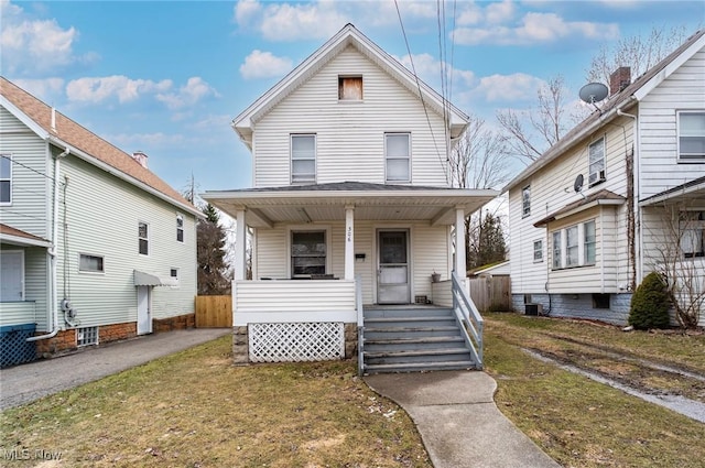 american foursquare style home featuring central AC unit, a porch, a front lawn, and fence