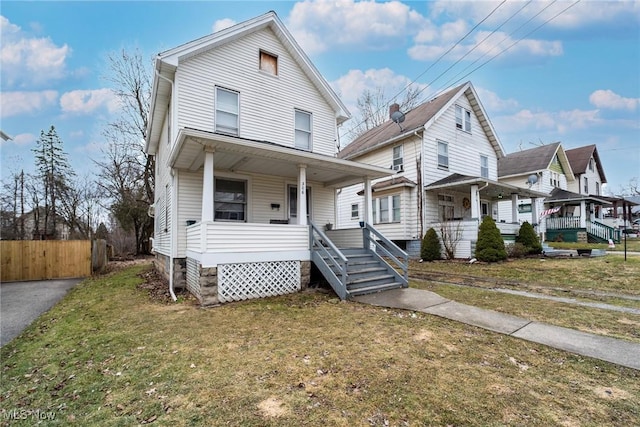 view of front of property featuring covered porch, driveway, a front yard, and fence