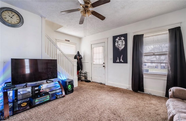 carpeted foyer entrance featuring ceiling fan, stairway, baseboards, and a textured ceiling