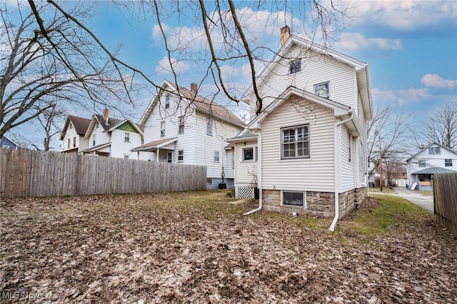 rear view of property featuring a chimney and fence