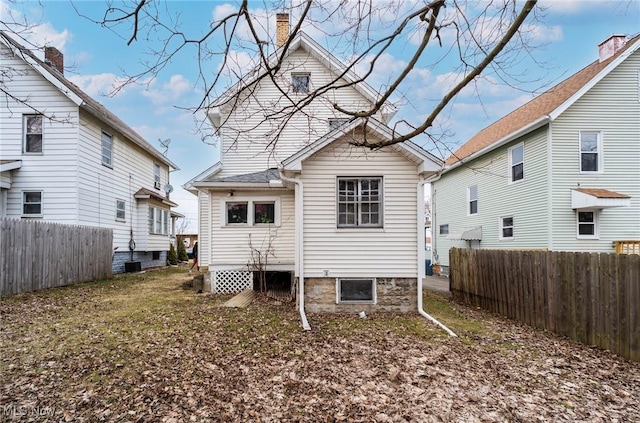 rear view of property with fence and a chimney