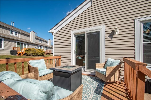 wooden deck featuring an outdoor living space with a fire pit